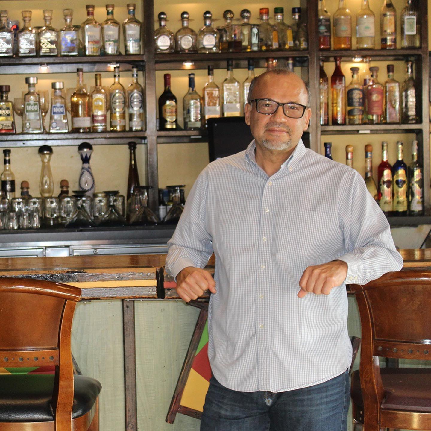 Baldo Cisneros, owner of Qué Pasa Mexican Cafe, standing at the bar in front of the tequila collection