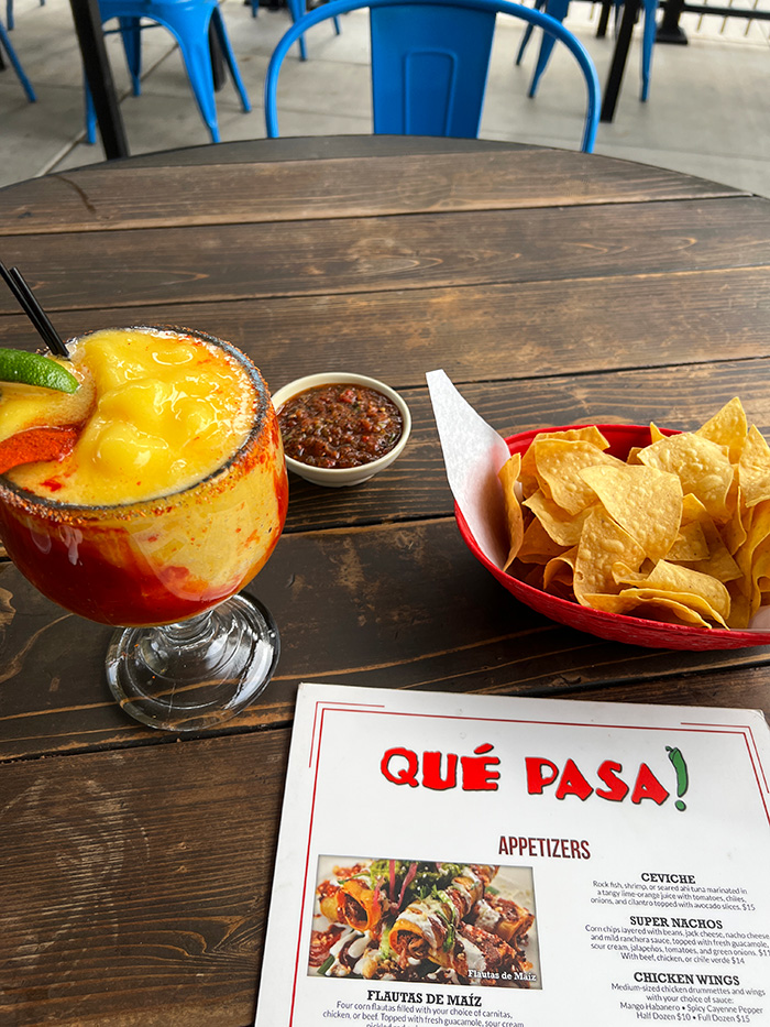 Frozen mango Mangonyada margarita with chili-salt rim beside chips and salsa