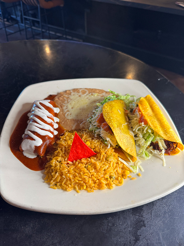 Red enchilada with two crispy tacos, Mexican rice and refried beans with cheese