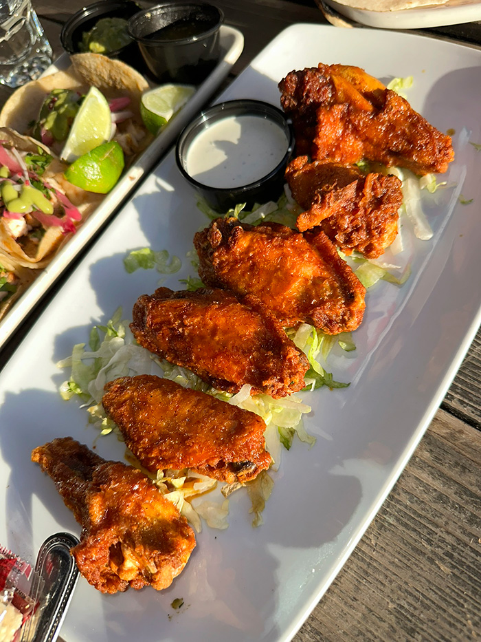 Row of spicy cayenne chicken wings on a white platter with ranch