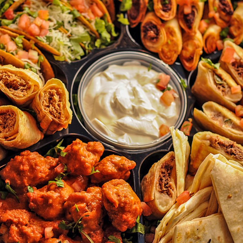 Overhead view of the Party Platter — segmented tray with wings, tacos, taquitos, quesadillas, and sour cream