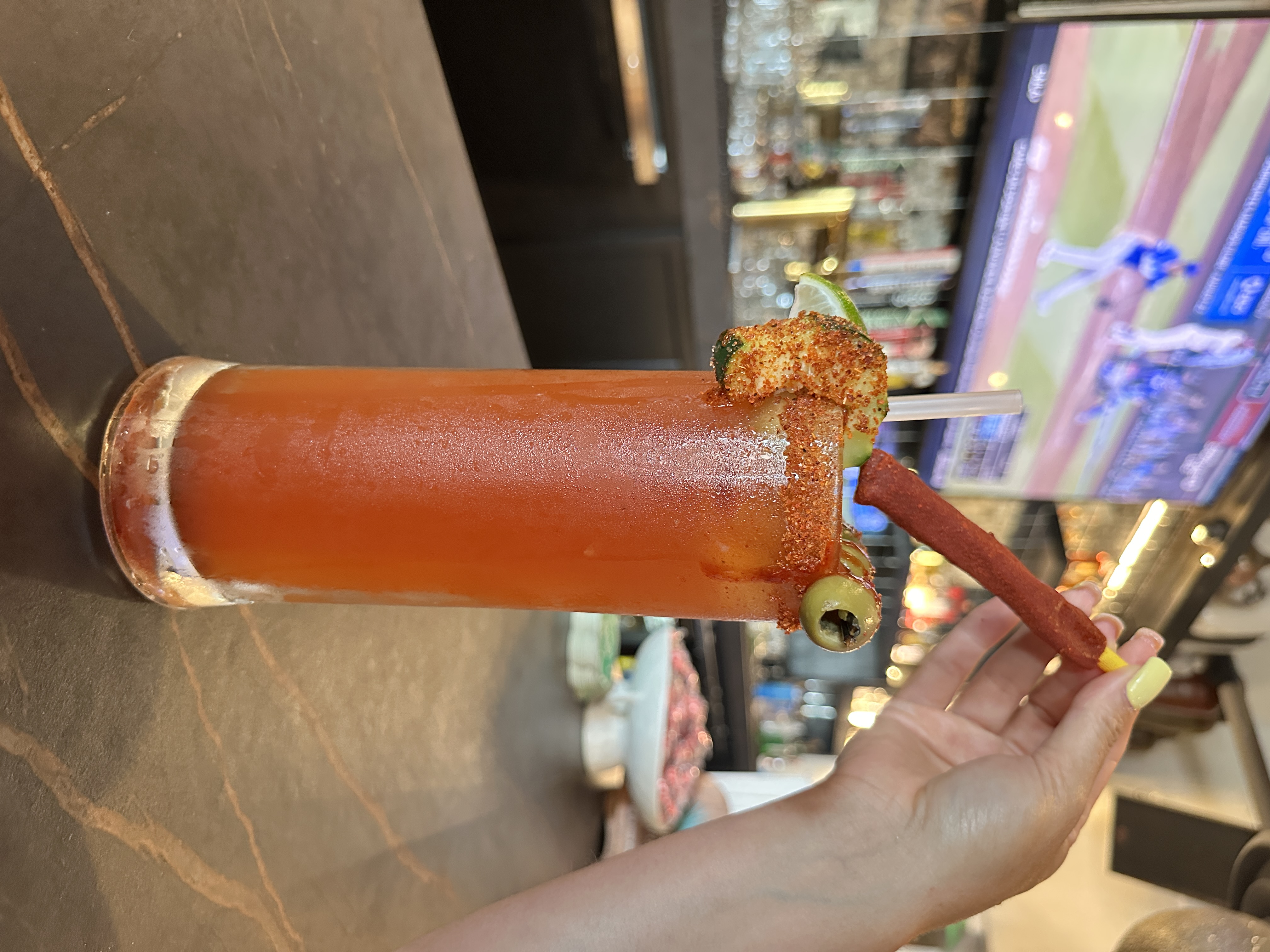 Tall Michelada with tajin-chamoy rim, tamarindo straw, olive and lime at the sports bar