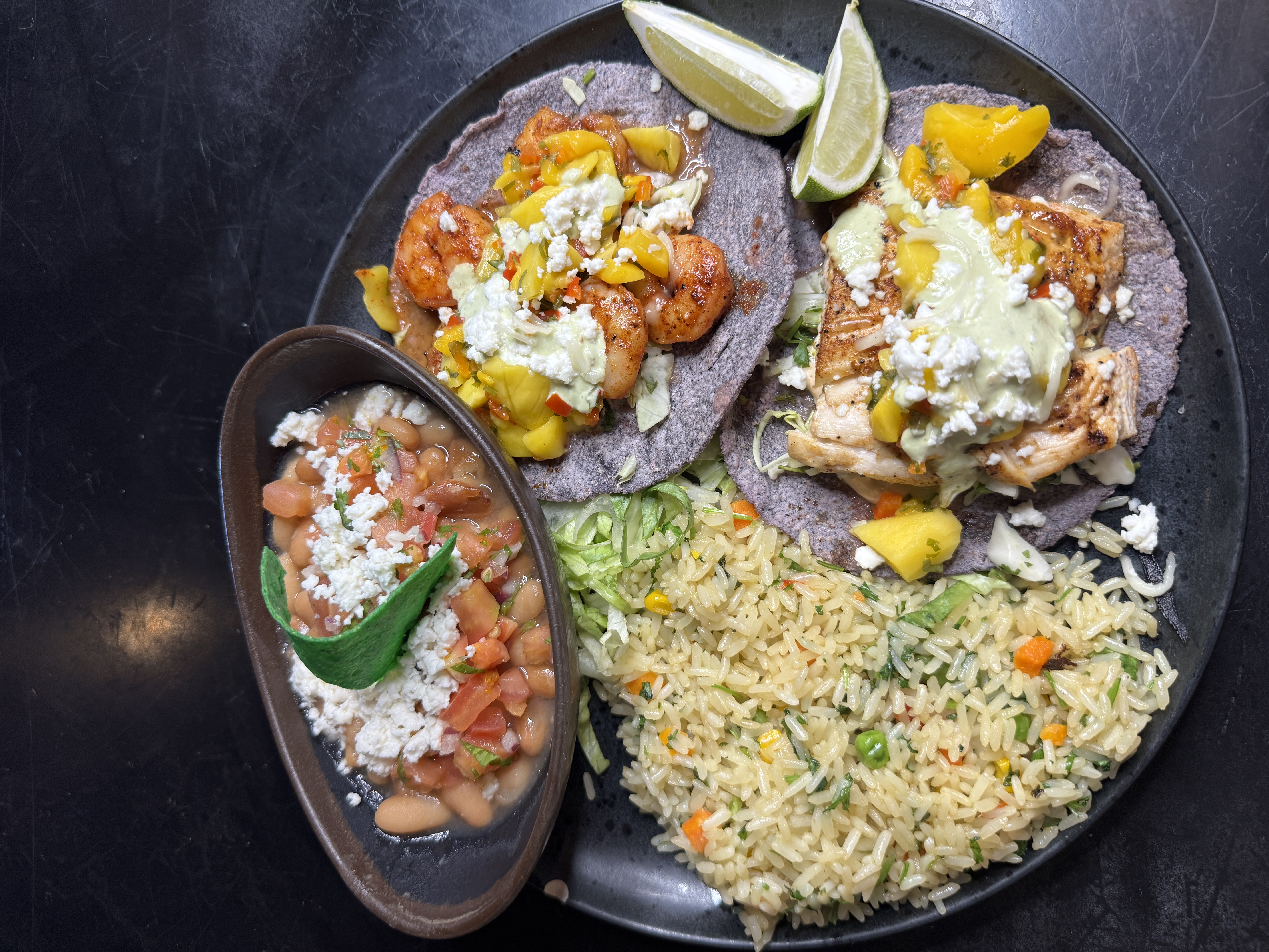 Grilled shrimp and fish tacos on blue-corn tortillas with mango salsa, plated with rice and pot beans